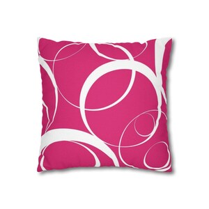 May include: A square decorative pillow with a vibrant fuchsia background. White, overlapping, free-form circles create a dynamic pattern across the pillow's surface. The pillow is a solid color on the back.