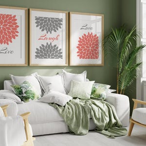 May include: Three framed prints with floral designs and the words "Live", "Laugh", and "Love" hanging on a green wall above a white couch with green throw pillows and a green blanket.
