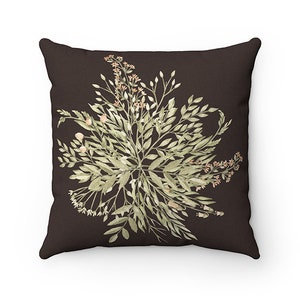 May include: A decorative throw pillow with a dark brown background. The pillow features a watercolor design of green and peach-colored botanical elements, including leaves and small flowers. The design is centered on the pillow.