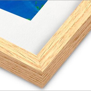 May include: Close-up of the corner of a natural wood picture frame. The frame has a light brown color and a smooth, slightly textured surface.