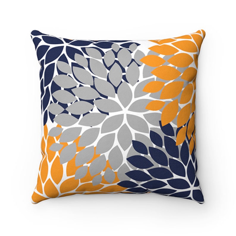 May include: A decorative cushion with a floral pattern in shades of navy blue, grey, and yellow. The cushion features a repeating pattern of stylised flower petals.