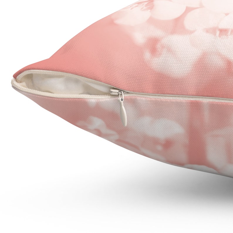 May include: A decorative pillow with a soft pink and white floral design. The pillow has a zipper closure and is made of a soft fabric. The pillow is a square shape and is perfect for adding a touch of elegance to any room.