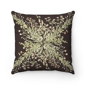 May include: Square throw pillow with a dark brown background and a floral design. The design features light green leaves, small beige flowers, and beige berries arranged in a symmetrical pattern.