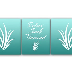 May include: A three-panel wall art set with a teal gradient background. Each panel features a white stylized grass design. The center panel has the words "Relax Soak Unwind" in a script font, with a smaller grass design.