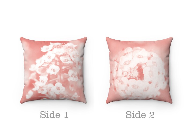 May include: Two square throw pillows with a floral design. The pillows have a soft coral background with a white floral pattern. The text "Side 1" and "Side 2" are printed below the pillows.