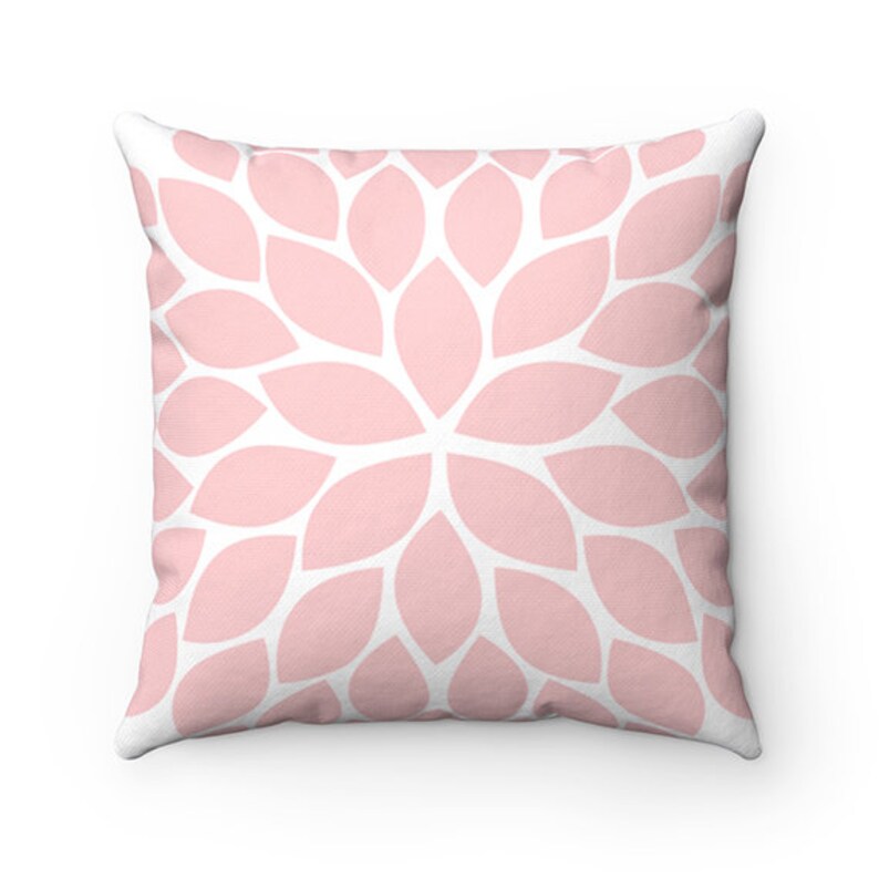 May include: A pink and white throw pillow with a floral pattern. The pillow is made of soft fabric and has a square shape.