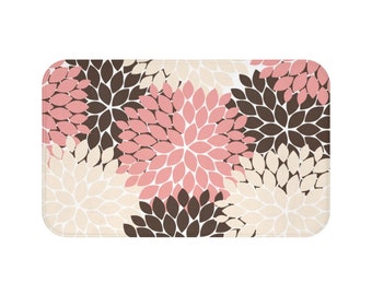 May include: A bath mat with a floral pattern in shades of pink, brown, and cream. The flowers are stylized and have a layered petal design.