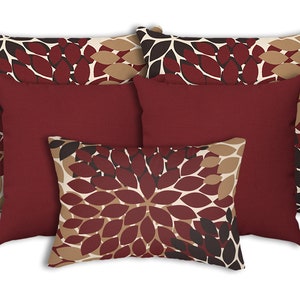 May include: Set of four decorative throw pillows with a leaf pattern in shades of brown, beige, and burgundy. The pillows are arranged in a pyramid shape, with the largest pillow at the bottom and the smallest pillow at the top.