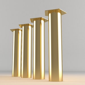 May include: Four gold metal table legs with square tops. The legs are arranged in a row from shortest to tallest.