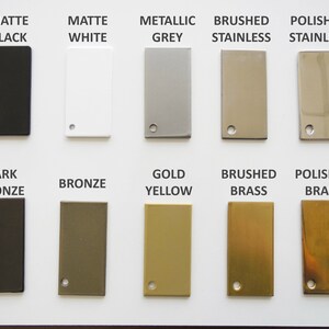 May include: A color palette featuring rectangular metal swatches in various finishes. The swatches include matte black, white, metallic grey, brushed and polished stainless steel, dark bronze, bronze, gold yellow, and brushed and polished brass. Each swatch has a small hole.