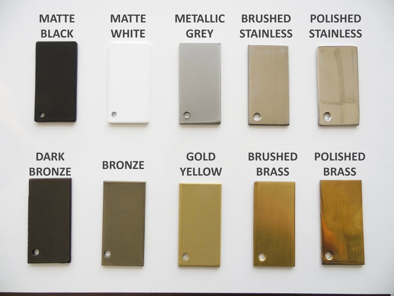 May include: A color palette featuring rectangular metal swatches in various finishes. The swatches include matte black, white, metallic grey, brushed and polished stainless steel, dark bronze, bronze, gold yellow, and brushed and polished brass. Each swatch has a small hole.