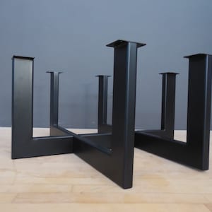 May include: Black metal table base with four legs and a crossbar design. The base is made of sturdy metal and has a black finish.