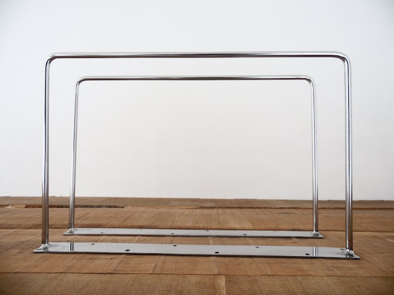 May include: Two chrome metal shelf brackets with a flat base and two vertical supports. The brackets are stacked on top of each other.
