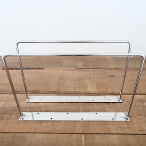 May include: Two silver metal shelf brackets with a rectangular base. The brackets are made of sturdy metal and are designed to support shelves.