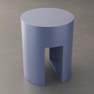 May include: A cylindrical, light blue side table with a cutout on one side. The table has a smooth, matte finish and a simple, modern design. The table is approximately 18 inches tall and 14 inches in diameter.