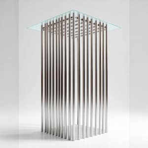 Puede incluir: Una mesa moderna de metal plateado con una tapa de vidrio transparente. La mesa tiene un diseño único con muchas varillas de metal verticales que forman la base.
