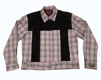 May include: A pink and black plaid jacket with a black zipper and a black collar. The jacket has a unique design with black panels on the front and back.