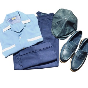 May include: A light blue button-down shirt with white piping, dark blue trousers, a dark blue cap, and two pairs of dark blue leather loafers.