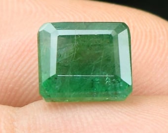 May include: A vibrant green emerald gemstone cut in a rectangular shape with a polished finish.