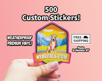 May include: Pink and yellow sticker with a brown and white dog sitting on a road with mountains in the background. The sticker says "NYDECALS.COM" and "WEATHERPROOF PREMIUM VINYL!"  500 Custom Stickers! Free Shipping. Made in Upstate, NY.