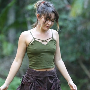 Puede incluir: Una mujer con una falda marrón con ribete de encaje y un top verde sin mangas. La falda tiene un diseño en capas y está atada a la cintura. La mujer está de pie en una zona cubierta de hierba.