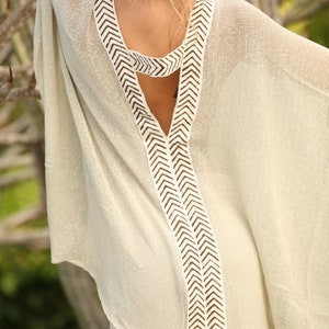 Pu&ograve; includere: Un top bianco in crochet con un motivo a chevron marrone sul collo e sulla schiena. Il top ha una scollatura a V profonda e una vestibilit&agrave; ampia e fluida.