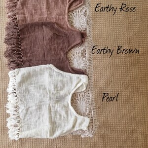 May include: Three crocheted tops with fringe trim. The top on the left is a light brown color, the middle top is a darker brown color, and the top on the right is white. The tops are labeled "Earthy Rose", "Earthy Brown", and "Pearl".