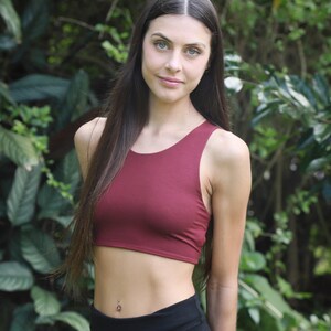 May include: A burgundy crop top and black leggings are worn in front of a green leafy background. The crop top is a solid colour with a scoop neck. The leggings are high-waisted. The Nature Spirit logo is in the bottom right corner.