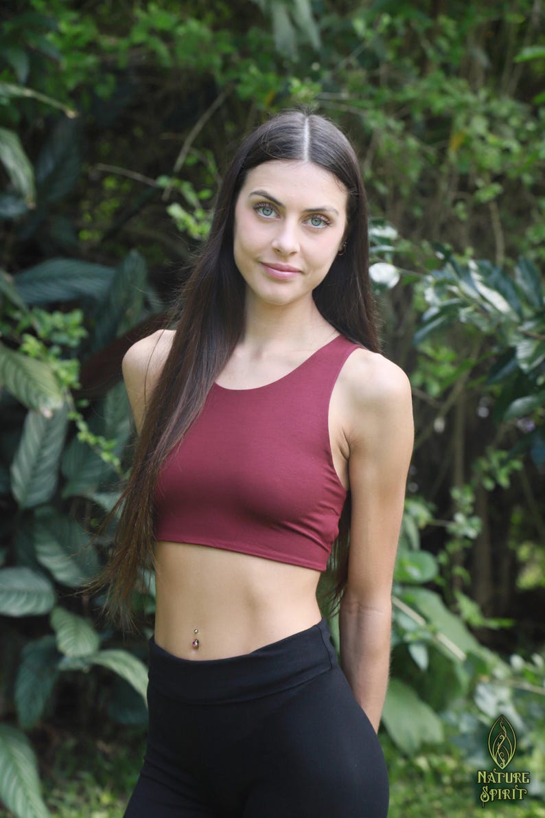 May include: A burgundy crop top and black leggings are worn in front of a green leafy background. The crop top is a solid colour with a scoop neck. The leggings are high-waisted. The Nature Spirit logo is in the bottom right corner.