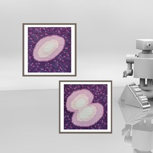May include: Two framed cross-stitch artworks. Each features a light pink and white oval design on a dark purple background. The frames are a neutral brown. A gray robot is in the background.