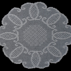 May include: A white, circular doily with an intricate crochet design. The doily features a central square pattern surrounded by oval and scroll-like motifs, and a scalloped edge. The detailed openwork creates a delicate, lacy appearance.