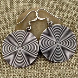 Può includere: Un paio di orecchini d'argento con un design a spirale. Gli orecchini sono rotondi e hanno una finitura liscia e lucida.