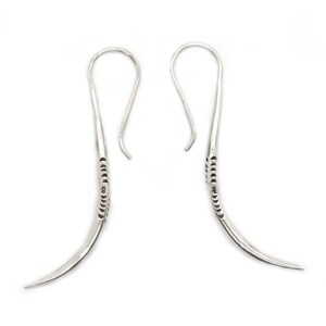 May include: A pair of silver dangle earrings with a curved design and a textured pattern. The earrings have a hook closure.