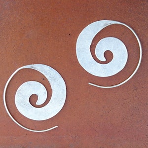 May include: A pair of silver earrings with a spiral design. The earrings are made of a thin metal wire and have a simple, elegant look.
