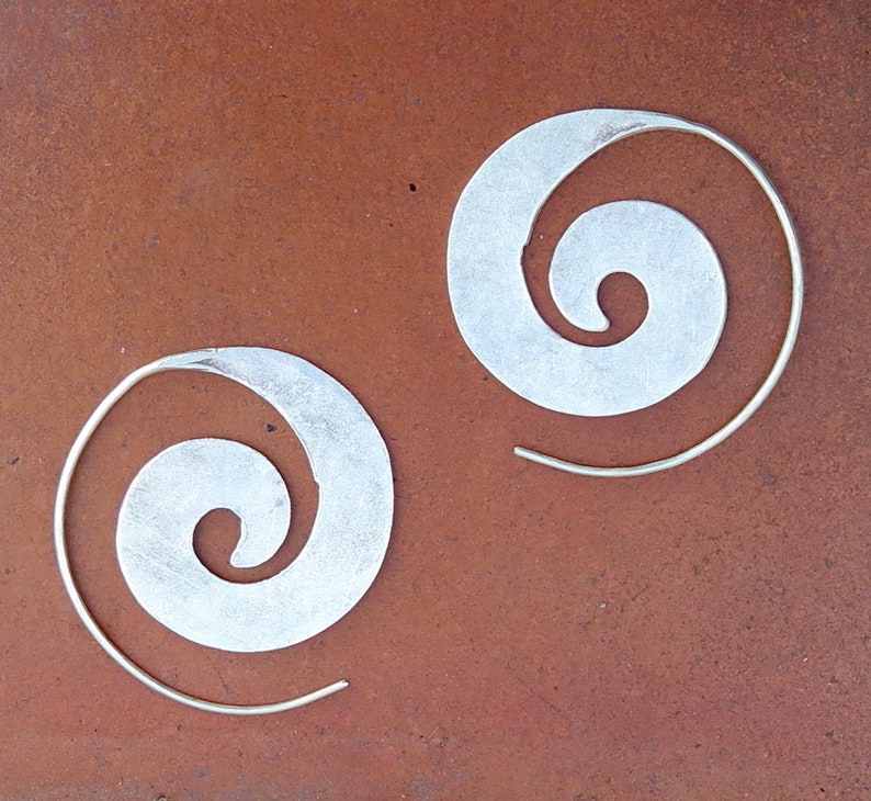 May include: A pair of silver earrings with a spiral design. The earrings are made of a thin metal wire and have a simple, elegant look.