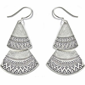 May include: Silver dangle earrings with a geometric pattern. The earrings are made of two layers of metal, each with a different design. The top layer is a triangle shape, and the bottom layer is a fan shape.