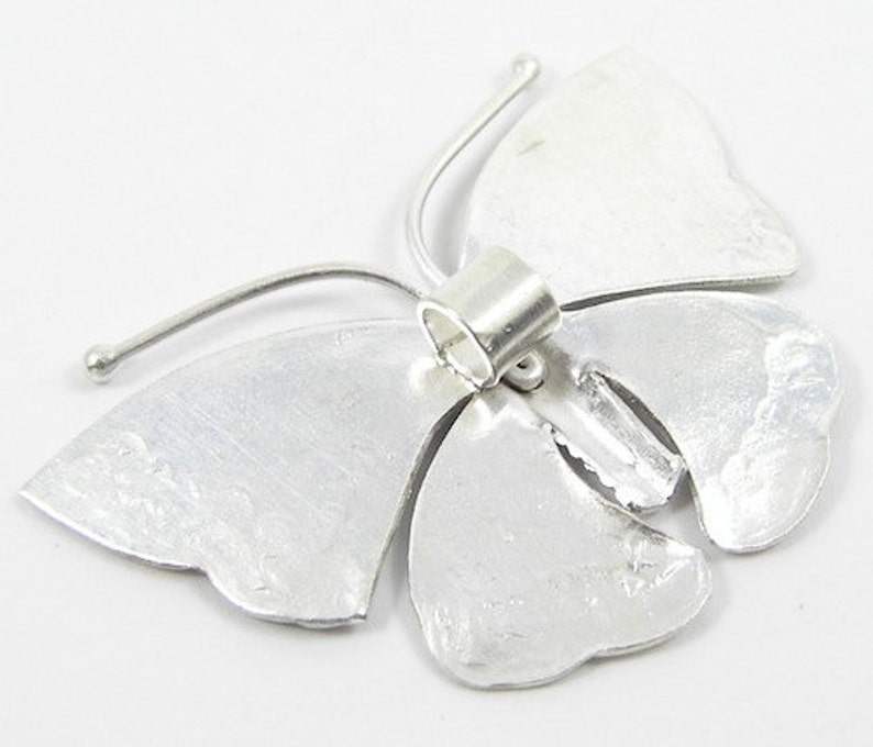 May include: Silver butterfly charm with a textured finish and a jump ring for attaching to jewelry.