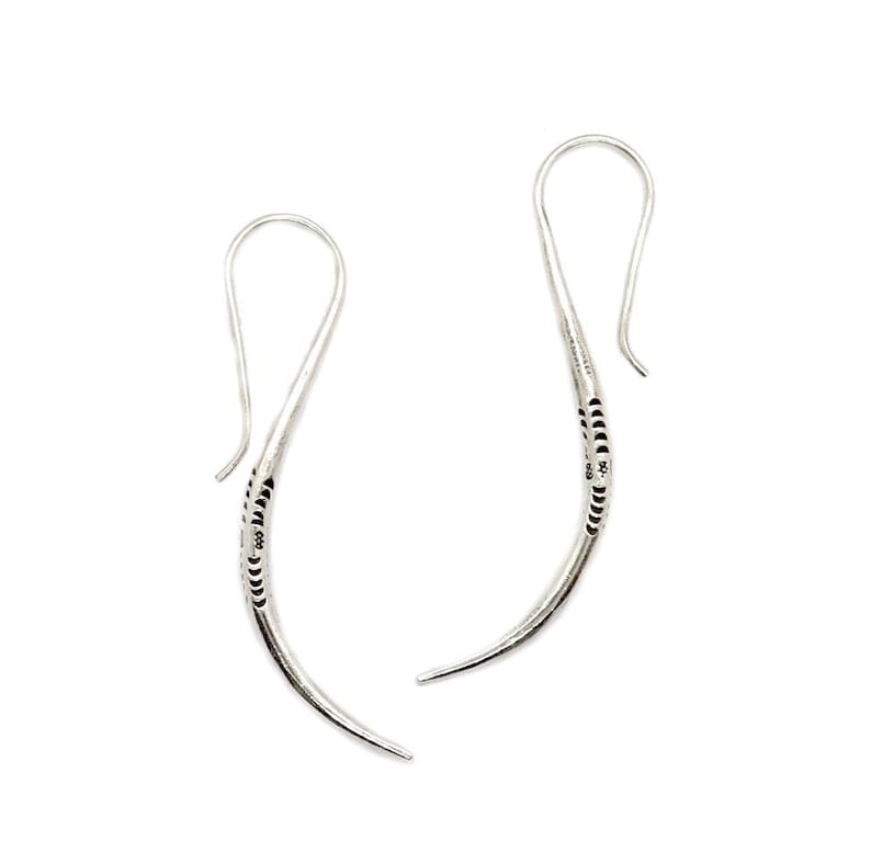 May include: A pair of silver dangle earrings with a curved design and a textured finish.