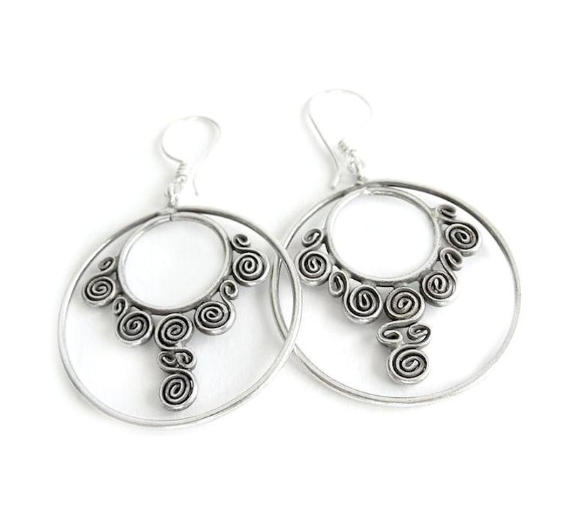 May include: Silver hoop earrings with a decorative design of swirling circles.