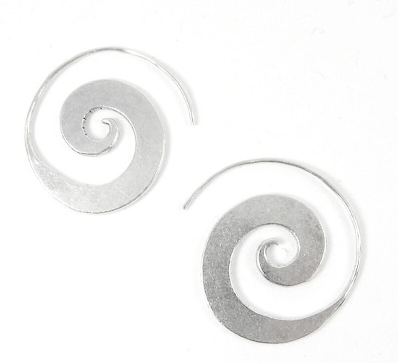 May include: A pair of silver spiral hoop earrings. The earrings are made of a thin metal and have a simple, elegant design.