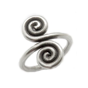 Puede incluir: Anillo de plata con dos diseños en espiral. El anillo está hecho de alambre que se retuerce en forma de espiral.
