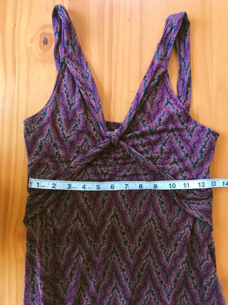 Puede incluir: Vestido morado sin mangas con un estampado de chevr&oacute;n en tonos marr&oacute;n, azul y negro. El vestido presenta un escote en V y un detalle de nudo en el busto. El vestido mide aproximadamente 33 cm de ancho en la cintura.