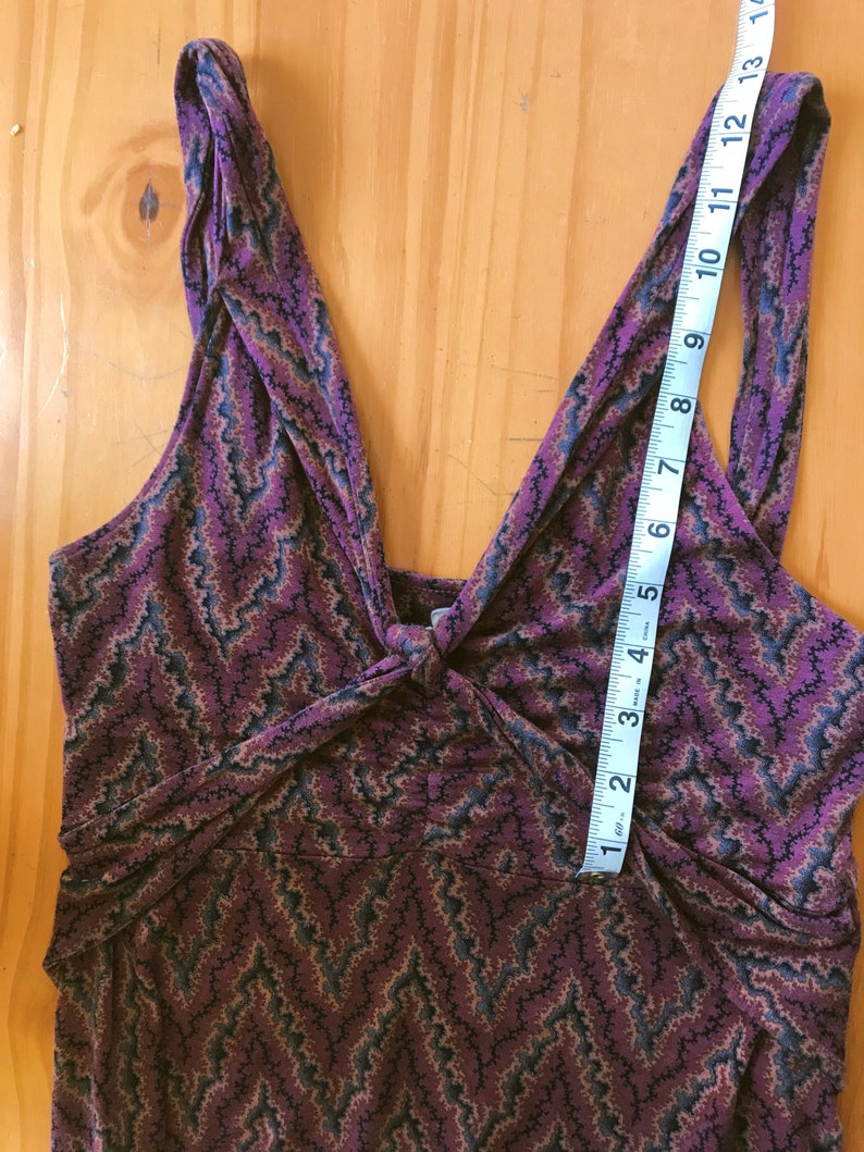 Puede incluir: Vestido sin mangas con estampado de chevr&oacute;n en tonos morado, negro y marr&oacute;n. El vestido tiene un detalle anudado en el busto y un escote en V. Una cinta m&eacute;trica muestra que el vestido mide aproximadamente 33 cm de largo desde la parte superior de la correa.