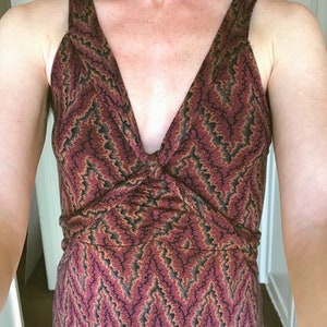 Puede incluir: Vestido sin mangas con escote en V y detalle anudado en el busto. El vestido presenta un estampado de zigzag burdeos, negro y beige. El vestido tiene un corpi&ntilde;o ajustado y una falda fluida.