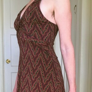Puede incluir: Vestido con cuello halter y estampado de chevr&oacute;n en tonos burdeos, marr&oacute;n y verde. El vestido tiene un corpi&ntilde;o ajustado y una falda fluida. La tela parece ligera, adecuada para climas c&aacute;lidos. El vestido mide unos 150 cm de largo.