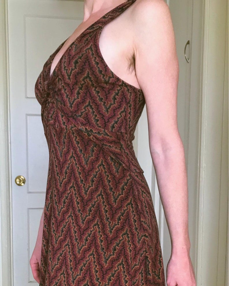 Puede incluir: Vestido con cuello halter y estampado de chevr&oacute;n en tonos burdeos, marr&oacute;n y verde. El vestido tiene un corpi&ntilde;o ajustado y una falda fluida. La tela parece ligera, adecuada para climas c&aacute;lidos. El vestido mide unos 150 cm de largo.