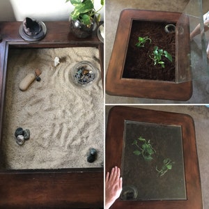 Op de afbeelding: Twee houten salontafels met glazen bladen. De bovenkant van de ene tafel is gevuld met zand en kleine stenen, terwijl de andere tafel een kleine potplant bevat.
