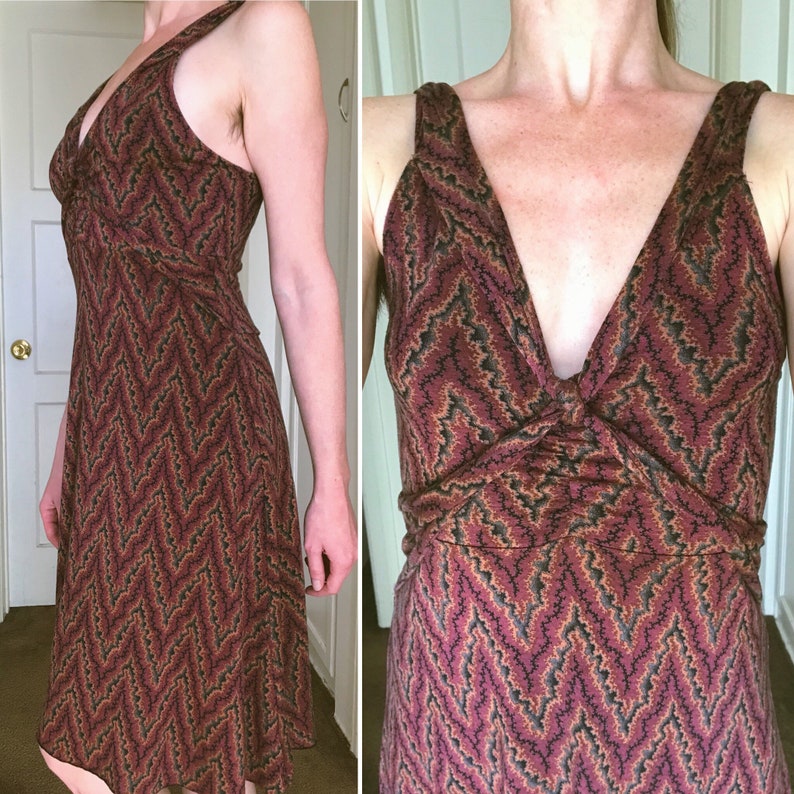 Puede incluir: Vestido sin mangas con escote en V y dise&ntilde;o estampado en tonos burdeos, negro y dorado. El vestido tiene un corpi&ntilde;o ajustado y una falda fluida, adecuado para diversas ocasiones.