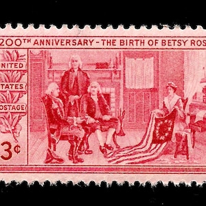 May include: A red 3-cent United States postage stamp commemorating the 200th anniversary of the birth of Betsy Ross. The stamp depicts a scene of Betsy Ross sewing the first American flag, with three men looking on.