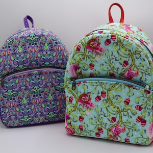 Puede incluir: Dos mochilas coloridas con patrones florales y geom&eacute;tricos. La mochila de la izquierda es morada con un patr&oacute;n geom&eacute;trico. La mochila de la derecha es azul con un patr&oacute;n floral.